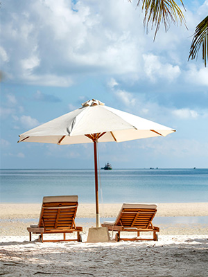Golden sandy beach with palm trees, turquoise waters, and a relaxing couple – JSBT Holidays